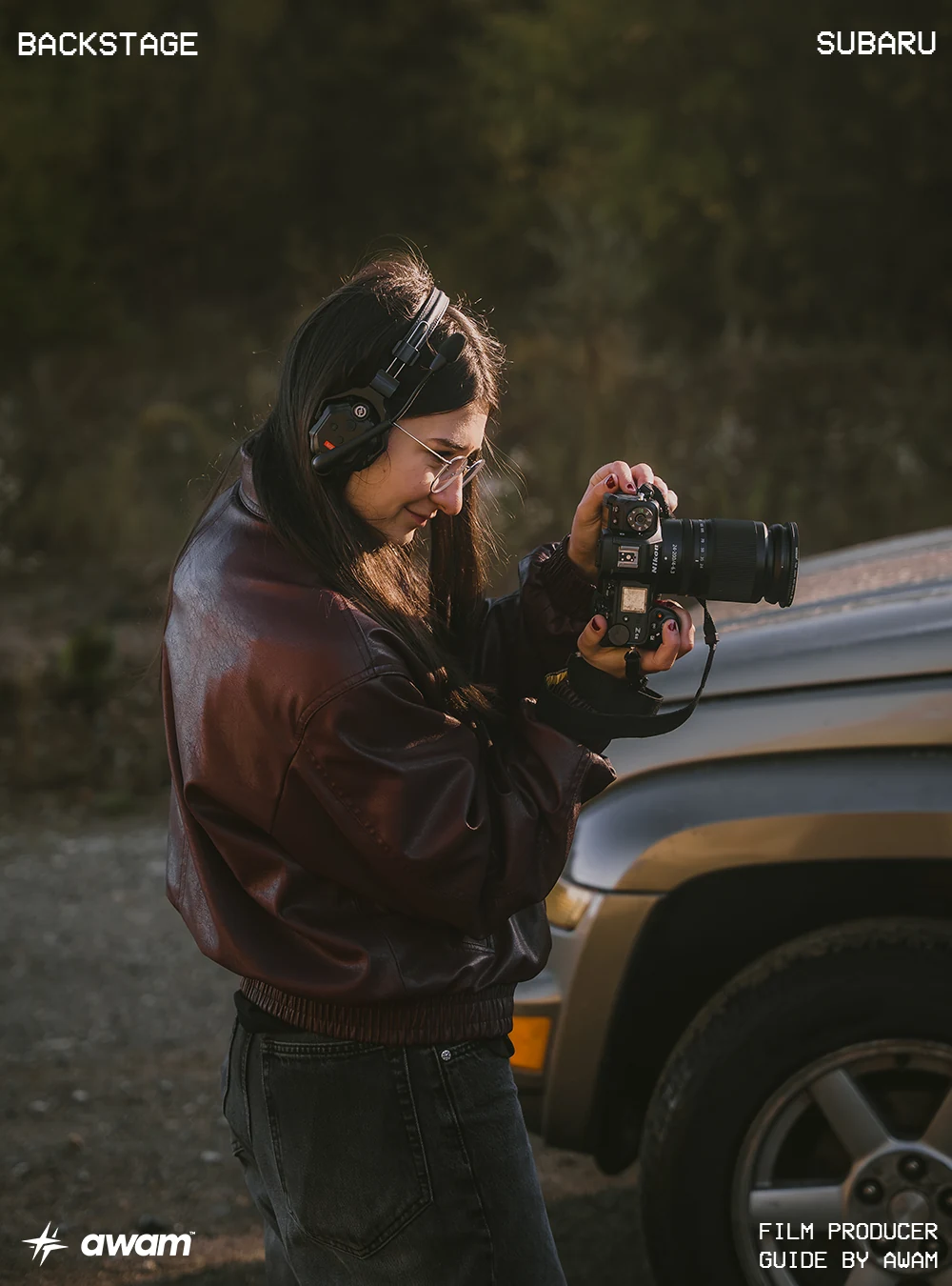 awam en el set: una fotógrafa con auriculares revisa una cámara junto a un vehículo al atardecer